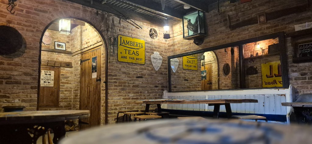 The Barn interior with exposed brick walls, wooden beams, communal table and vintage Lamberts Teas signage