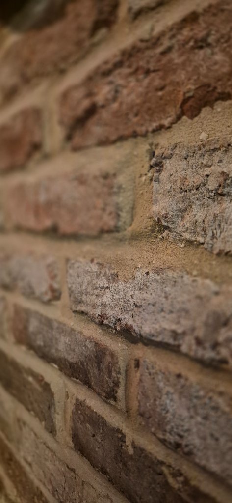 Weathered Victorian brick wall with gritty mortar and warm terracotta tones